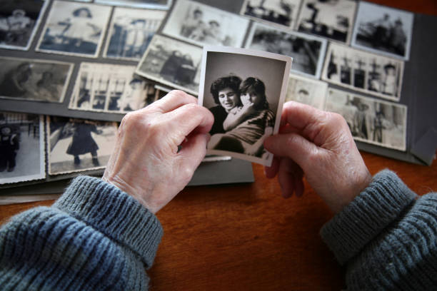 Elderly hands looking through old family photos on a wooden table